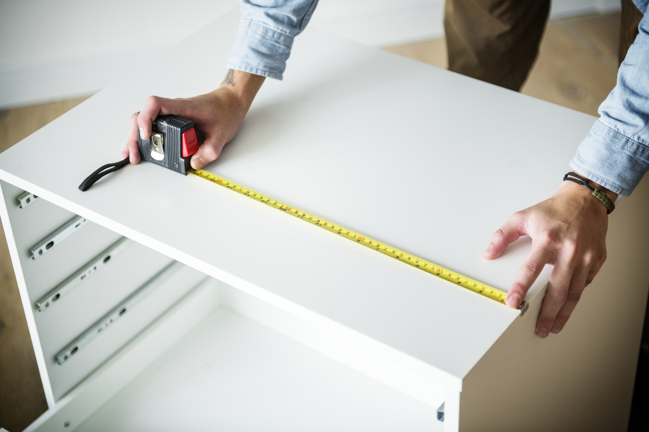 A man's hands measuring a small table